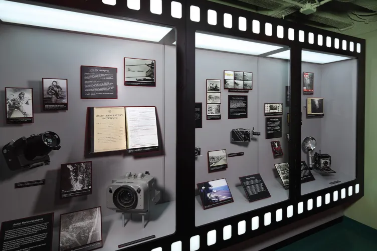 Photos and cameras are displayed in an exhibition case.