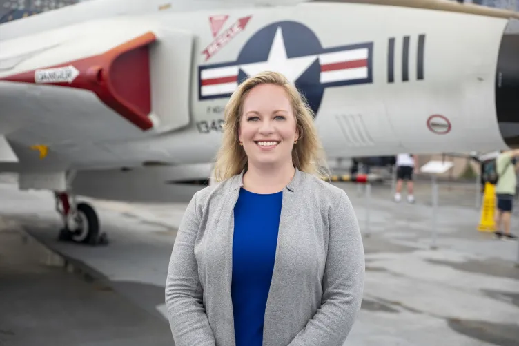 Danielle Swanson standing on the Intrepid flight deck in front of an aircraft.