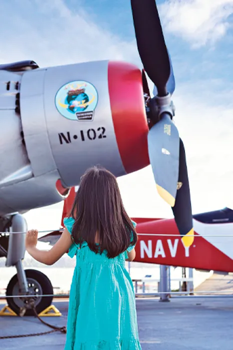 A little girl is looking at an aircraft on the flight deck.