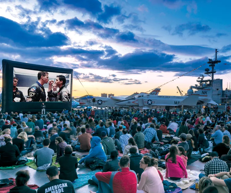Movie Night Crowd at the Flight Deck during sunset, large movie screen, and Aircraft in the background 