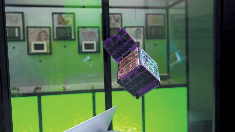 A holographic cube is suspended in mid-air in a display case.