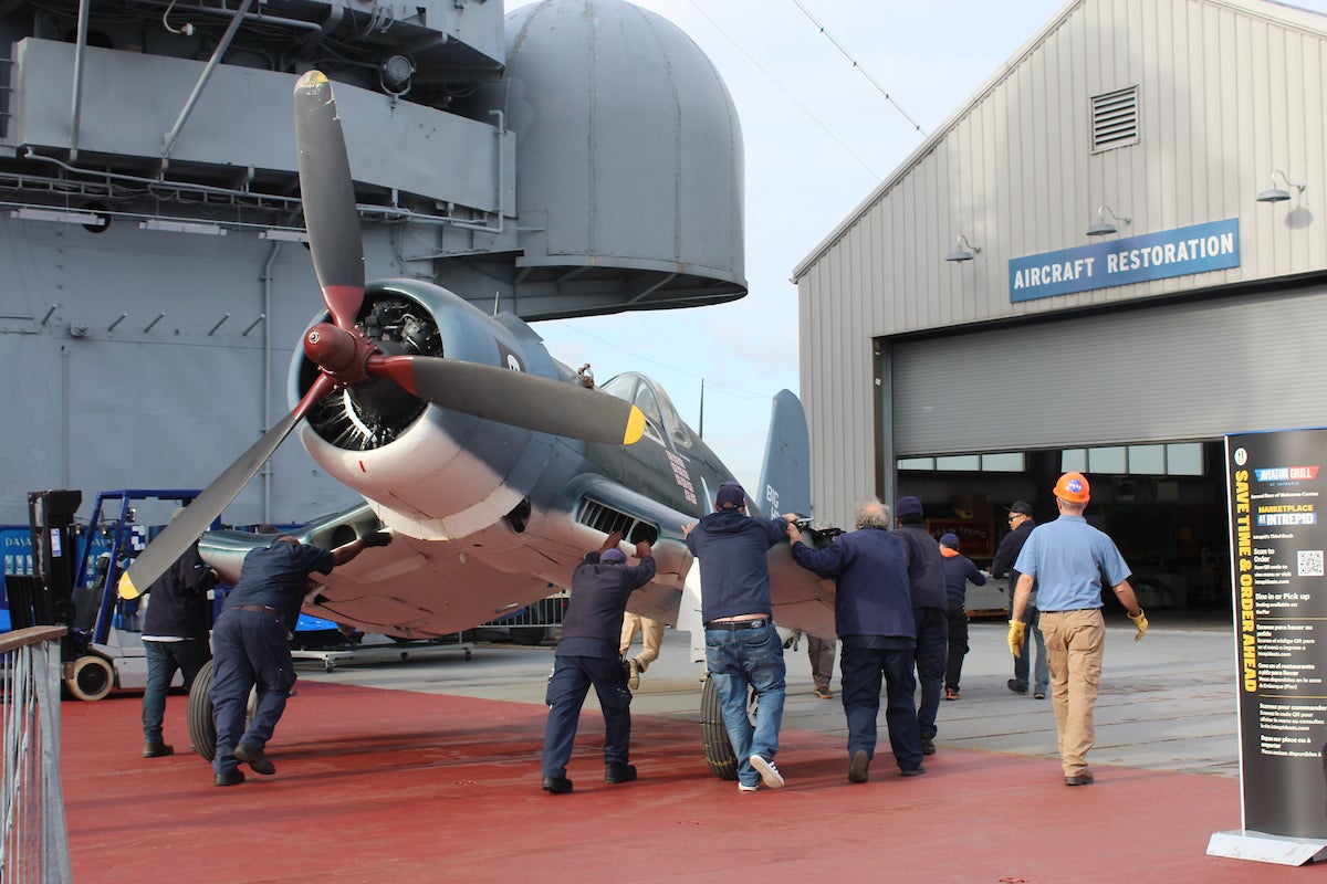 Intrepid Museum employees moving the newly arrived Corsair into the Aircraft Restoration Hangar to begin its repainting and restoration. Credit: Intrepid Museum. 