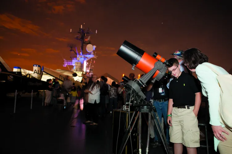 People using telescopes on the flight deck to look at the night sky.