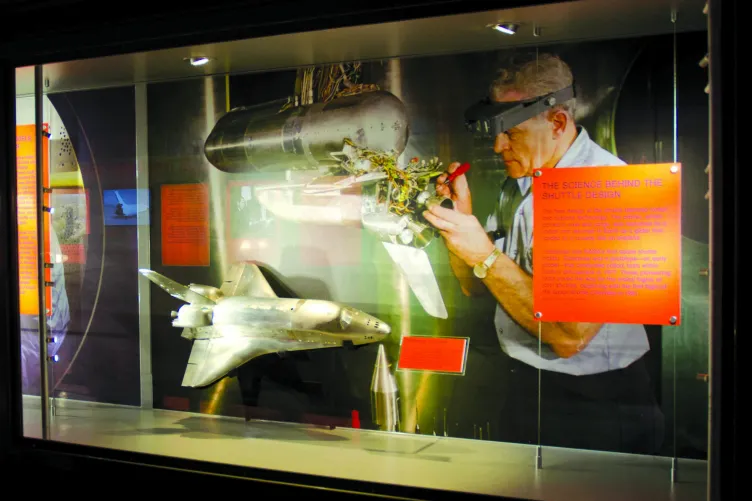 An exhibition panel that reads: "The Science Behind the Shuttle Design." The panel shows the Enterprise and an engineer working on a piece of it.