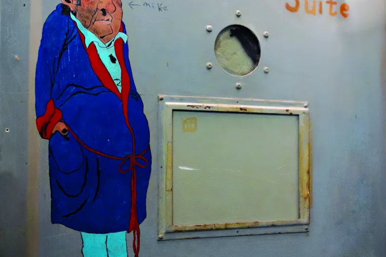 Sailor art on a sick bay door depicting a bruised and injured man in a robe, with the text "Intrepid's Suite" written next to him.