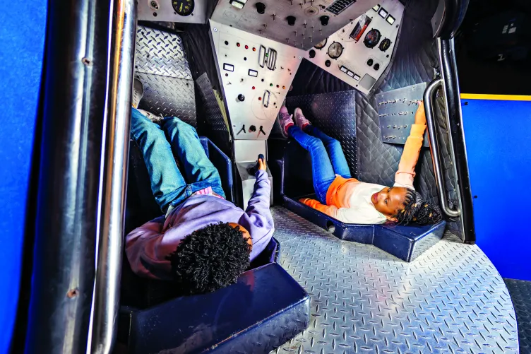 Two children play inside a mock space capsule located in the Museum&#039;s Exploreum