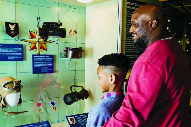 A father and son view artifacts related to the kamikaze attacks Intrepid endured during WWII