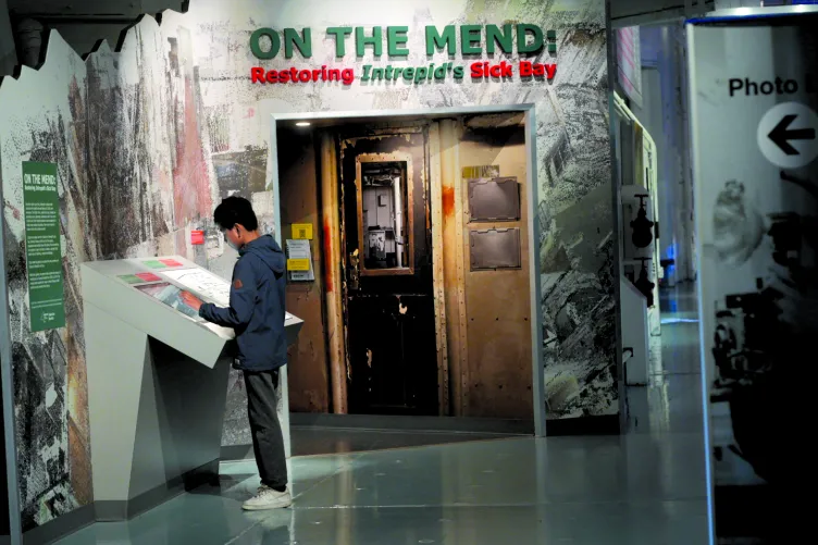 A visitor reads a panel in front of the exhibition &quot;On the Mend: Restoring Intrepid&#039;s Sick Bay.&quot;