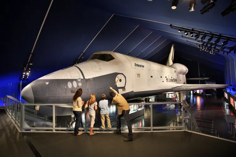 A family looks at the space shuttle Enterprise from an elevated viewing platform inside the Space Shuttle Pavilion