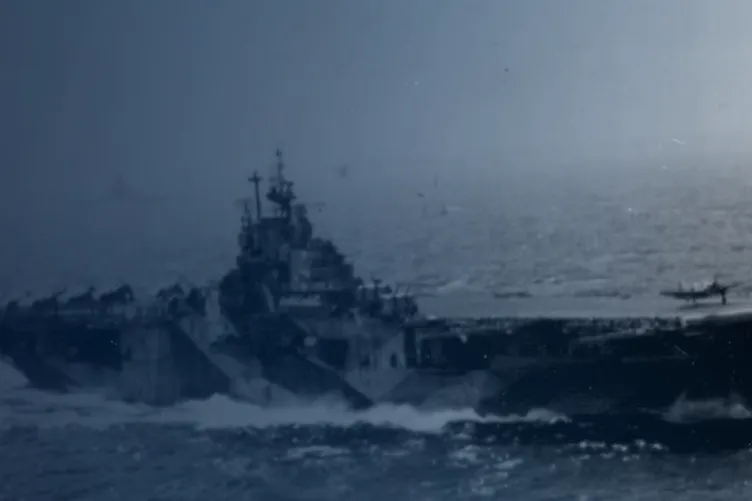 A somewhat faded old image of the USS Intrepid in the ocean