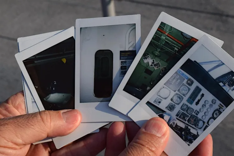 holding polaroid pictures of onboard the intrepid museum