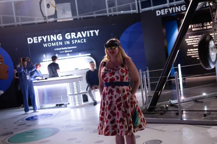 A woman wearing a VR headset in the exhibition “Defying Gravity: Women in Space.”