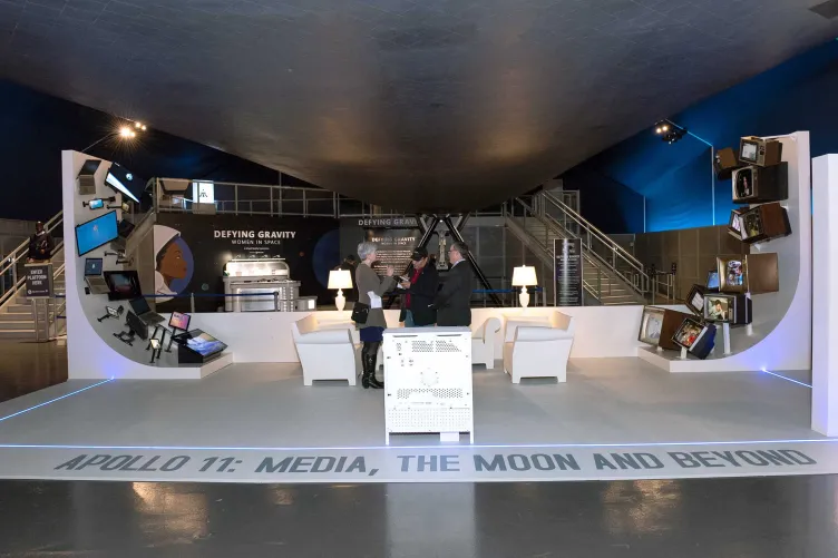 An exhibition beneath the Enterprise with couches and several different screens.