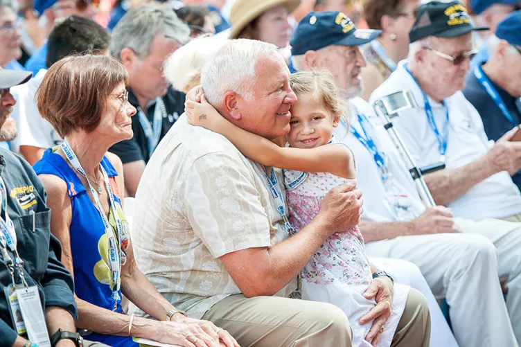 A young girl is hugging an older man in a row of seating