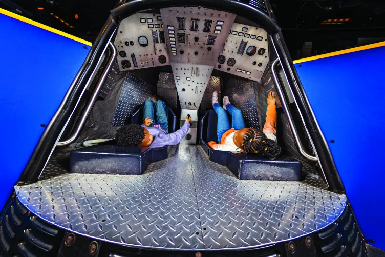 Two children playing in a mock capsule in the Exploreum.