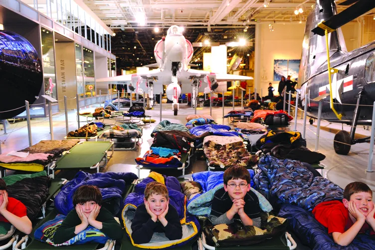 A group of children in sleeping bags on the hangar deck.