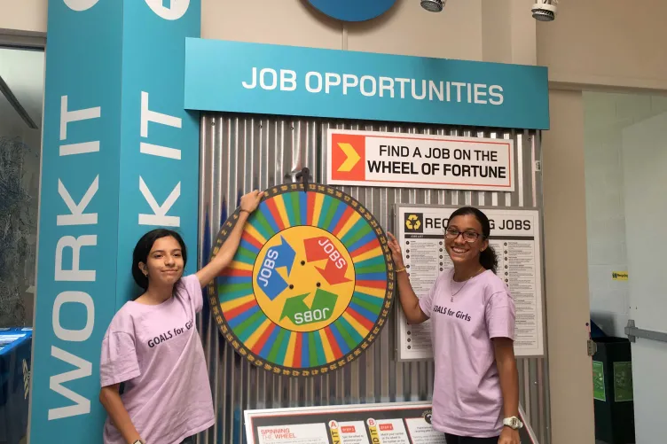 Two young people with a large rotating wheel