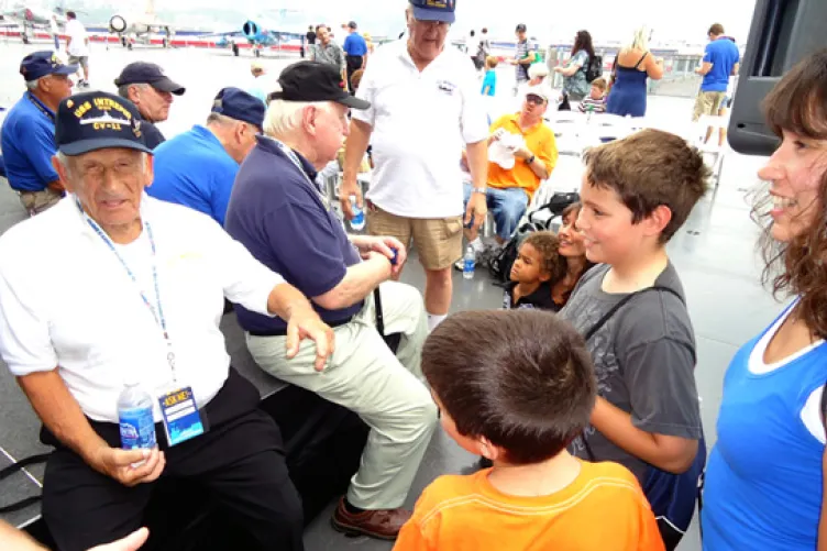 intrepid former crewmembers talking to museum visitors after the ceremony