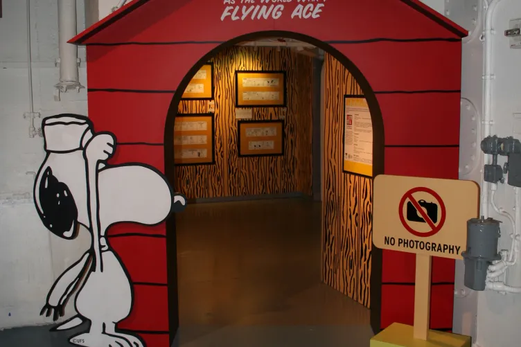 An opening to an exhibition that says “Snoopy as the World War I Flying Ace” with a cartoon dog next to it.