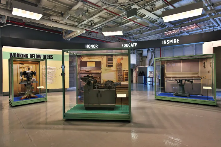 Three large exhibition cases that display various pieces of equipment that were used by workers below deck.