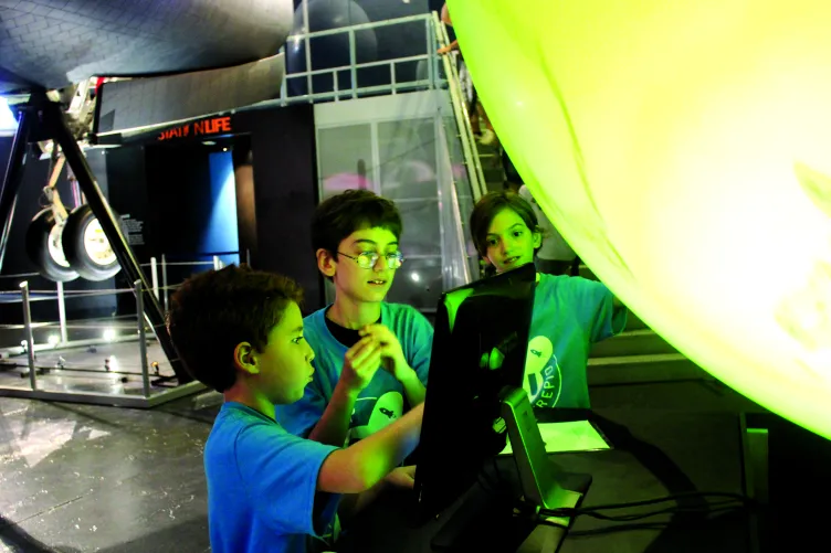 Students looking at a monitor in the Space Shuttle Pavilion