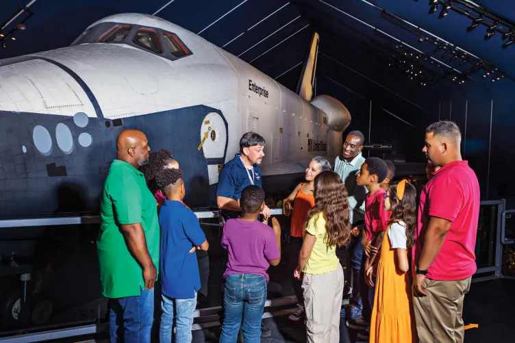 Group of visitors with a museum guide in front of the Space Shuttle Enterprise