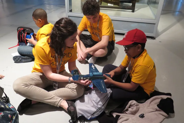 Group of kids touching a aircraft model with an educator