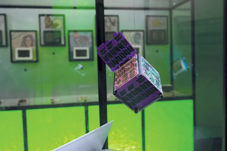 A holographic cube is suspended in mid-air in a display case.