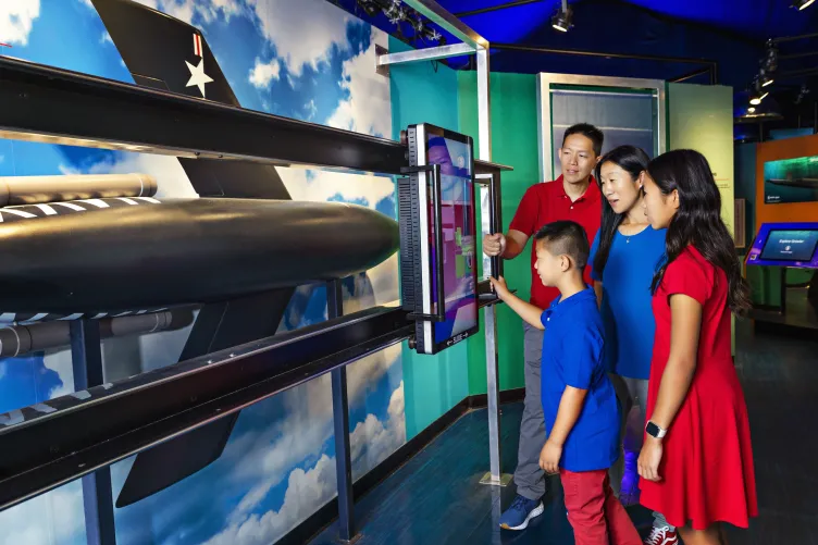 Family exploring a digital display, part of a View From the Deep: The Submarine Growler and the Cold War exhibition.