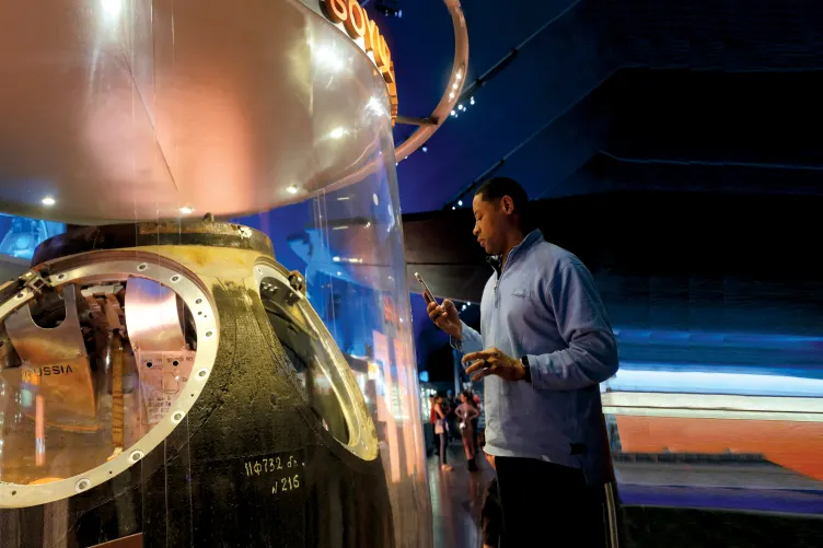 Man looking inside the Soyuz capsule exhibit