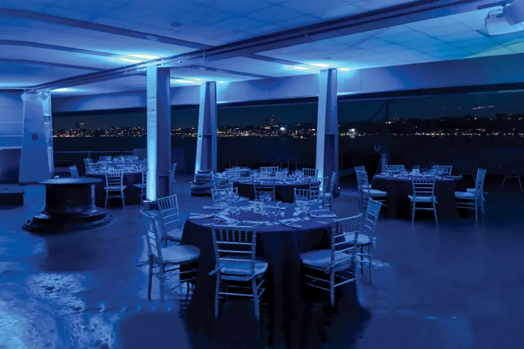 Photo of the Fantail setup for a seat down dinner with a view of the Hudson River and New Jersey skyline.