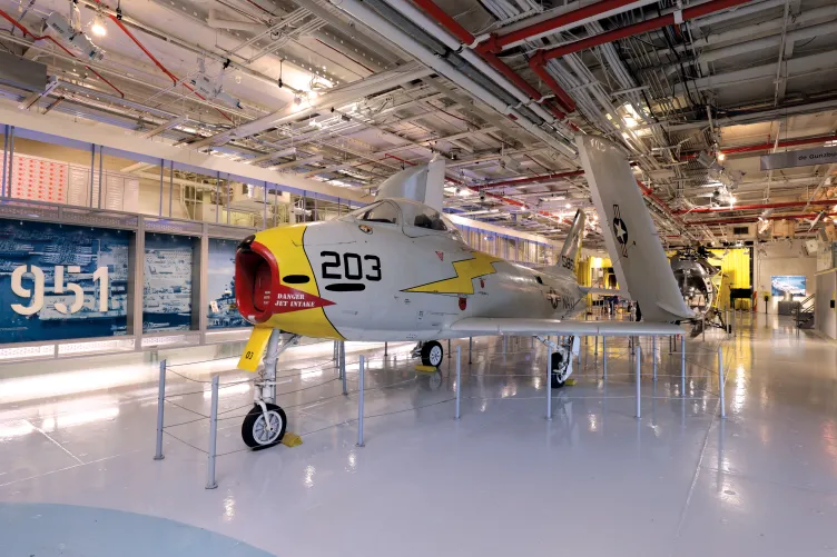 White, yellow and red FJ-3 FURY Aircraft displayed at the Hangar Deck.