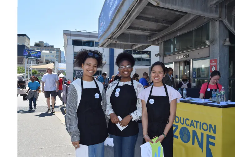 image of three GOAL girls in front of an education zone table