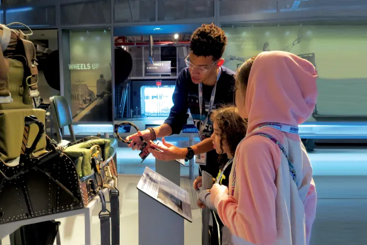 A Museum educator shows two girls how aircraft ejection seat works