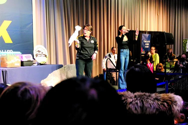 A presenter from the Zoo holding a bird on stage in the Exploreum hall during Kids Week.