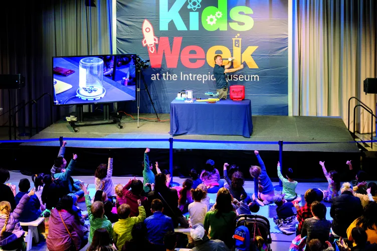 An Intrepid Museum educator presenting to kids in the Exploreum interactive hall during Kids Week