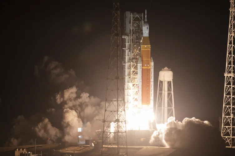 A rocket beginning to launch, surrounded by smoke.