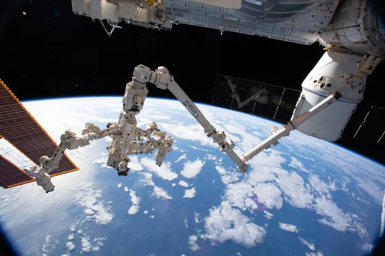 A robotic arm is outstretched over the Earth.