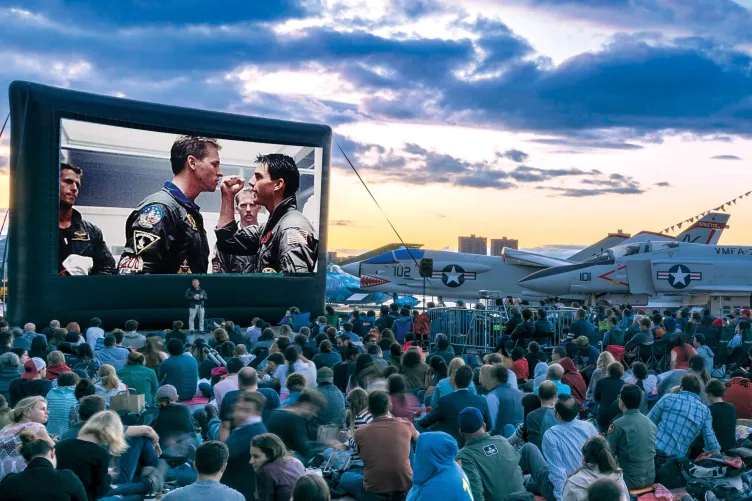 Movie Night Crowd at the Flight Deck during sunset, large movie screen, and Aircraft in the background.