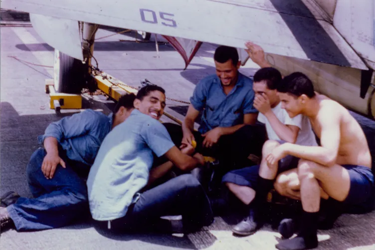 A group of Spanish sailors sitting on the flight deck of the Intrepid.