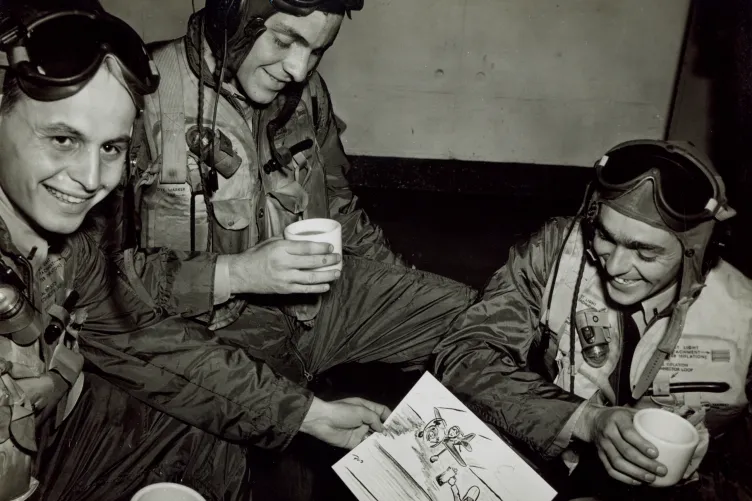 Three crew members sharing coffee while examining a sketch of fellow crew members on the flight deck.