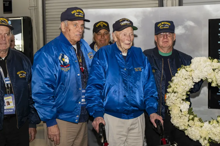 Veterans standing next to a wreath made of white flowers