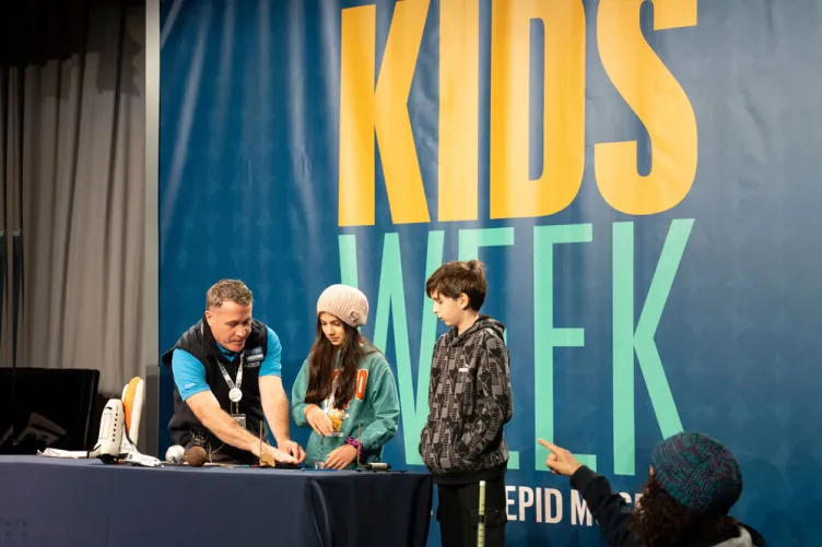 An educator on stage engaging a children in  an interactive activity during Kids Week