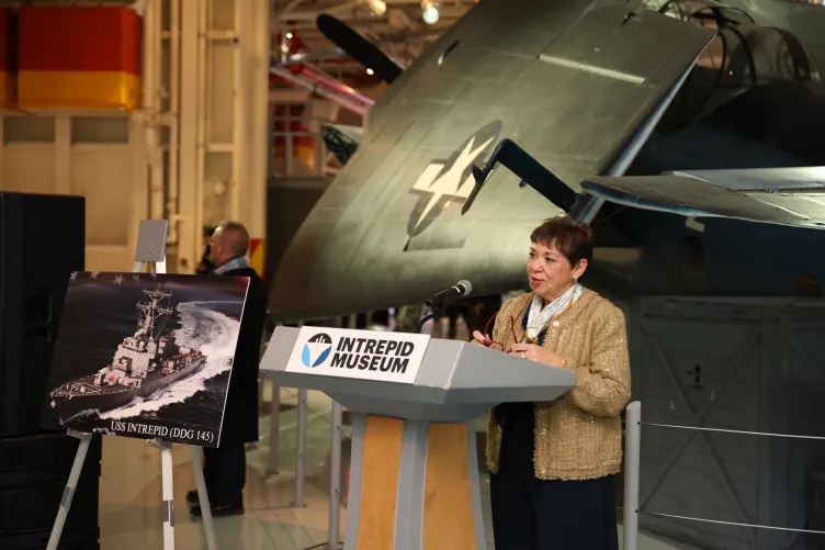 Mrs. Betty Del Toro stands at the podium during a ceremony at the Intrepid Museum.