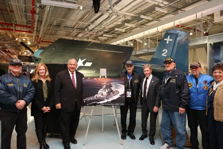 A group of people stand together on the hangar deck of the Intrepid Museum.