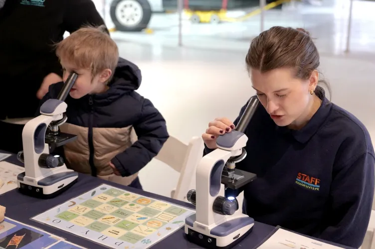 A child and an adult looking into a microscope during Kids Week.