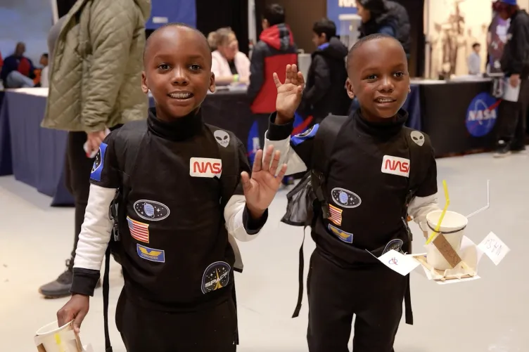 Two boys dressed as astronauts excitedly explore their surroundings during Kids Week