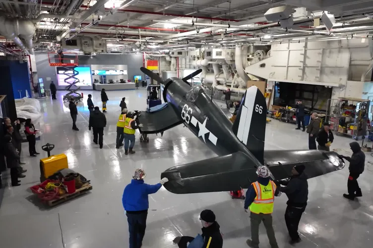 Corsair aircraft inside the Intrepid Museum's hangar deck being moved into its permanent exhibition spot.