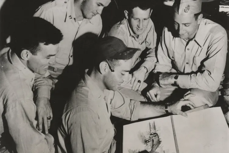 An archival photo showing veterans gathered around, observing one of them as they draw.