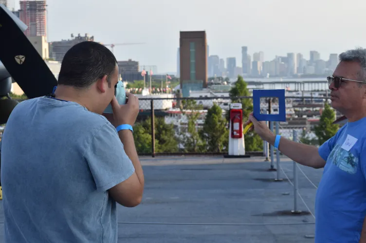 A young man takes a photo of a rectangular frame held by another man